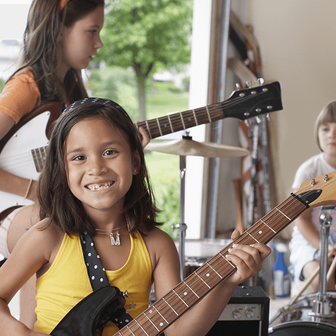 Young girls smiling and playing a guitar