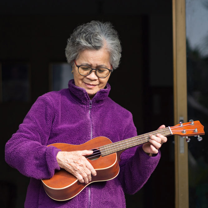 Woman in purple sweater playing ukulele
